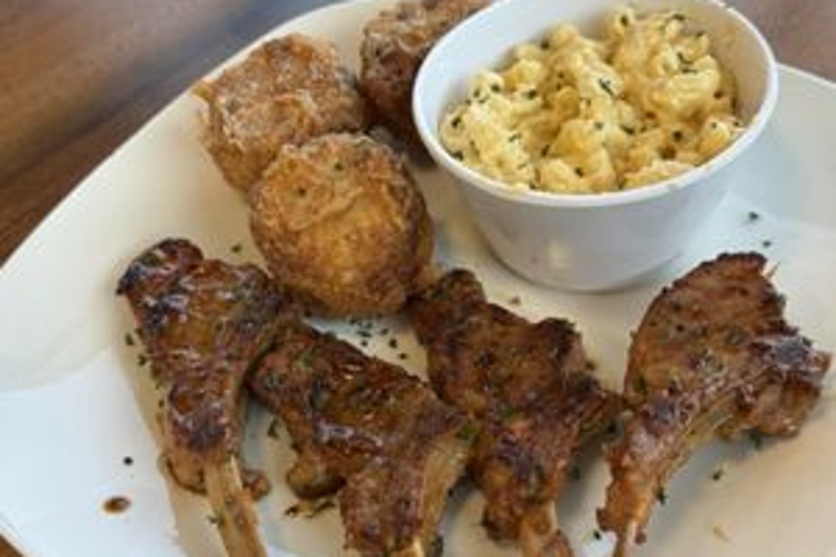 Grilled lamb chops with fried sides and a bowl of macaroni and cheese at Kitchen 11 Eleven