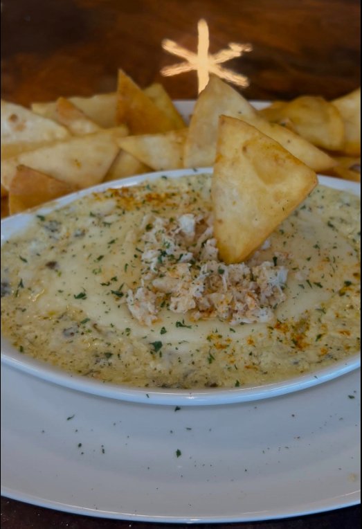 Crab spinach dip topped with lump crab and herbs, served with warm tortilla chips
